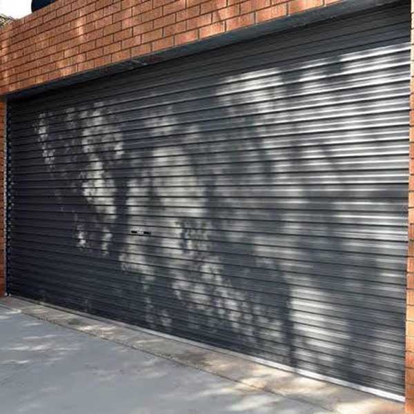 black double garage door with a brick wall