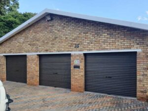 3 black garage doors with brick wall